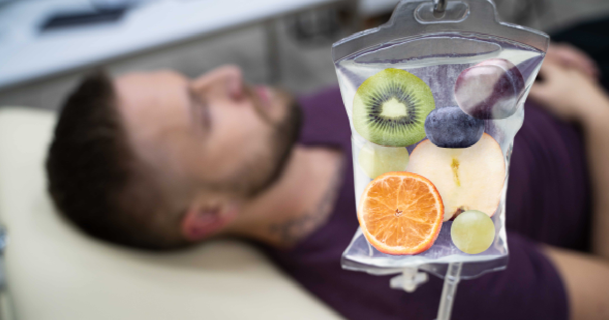 Man receiving IV Therapy in Bismarck, ND, with a focus on a transparent IV bag creatively filled with fruit slices representing vitamin-rich infusion.