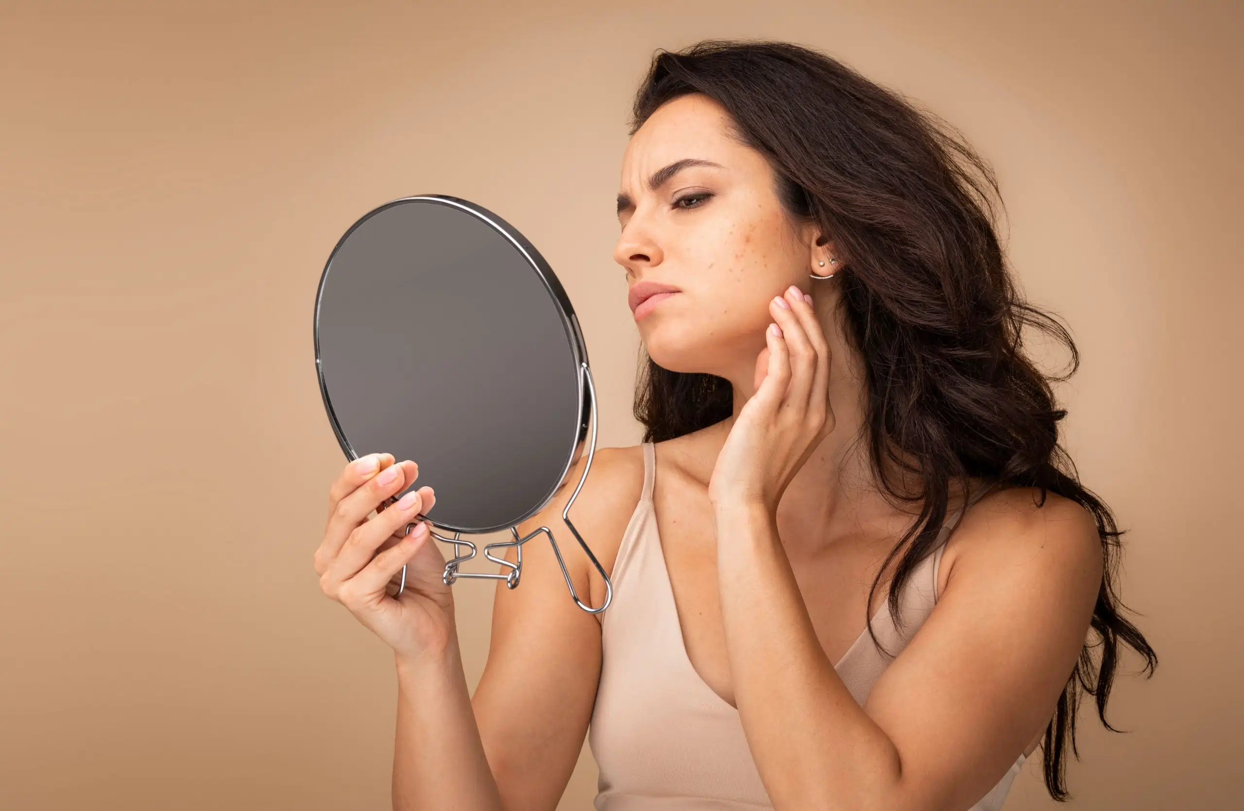 Woman seeing her face in mirror for skin issues before aesthetic treatment in Bismarck, ND